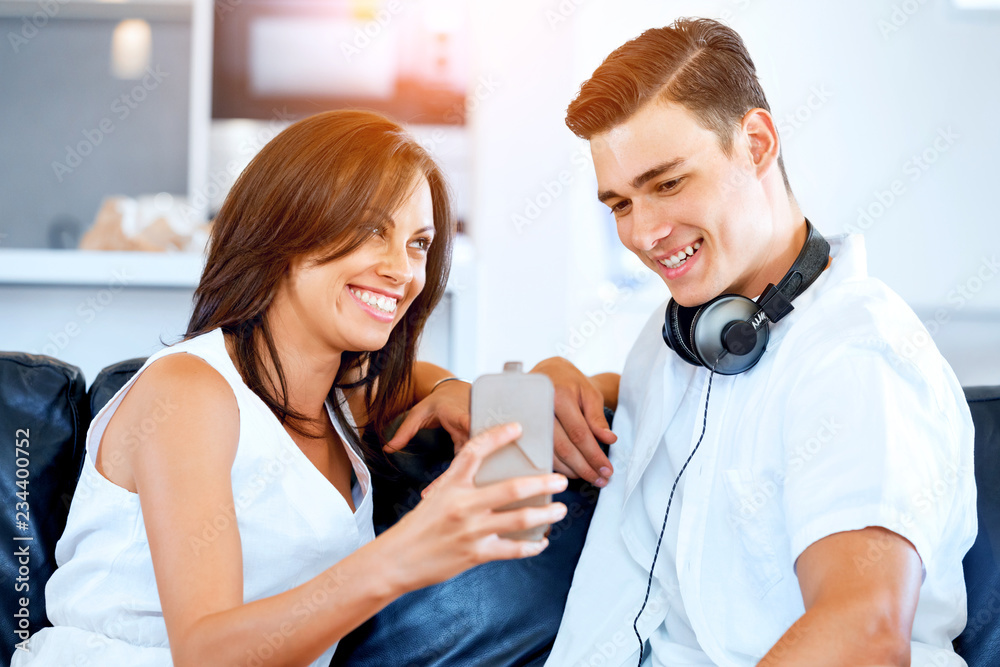 Young couple looking at mobile phone while sitting at home Young couple looking at mobile phone while sitting at home