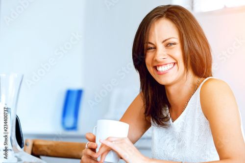 Happy young woman with cup of tea or coffee at home © Sergey Nivens