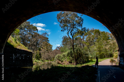 Girl Stands in Silhouette Underneath Massive Archway Bridge