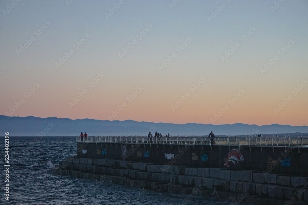 Obraz premium Victoria, British Columbia, Canada: Ogden Point Breakwater (1916) with the Strait of Georgia behind it and the mountains of Olympic National Park (Washington, USA) in the distance, at sunset.