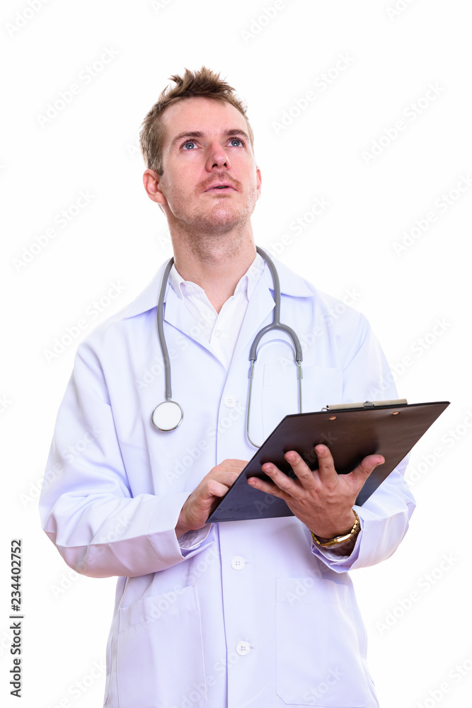 Studio shot of man doctor holding clipboard while thinking Studio shot of man doctor holding clipboard while thinking
