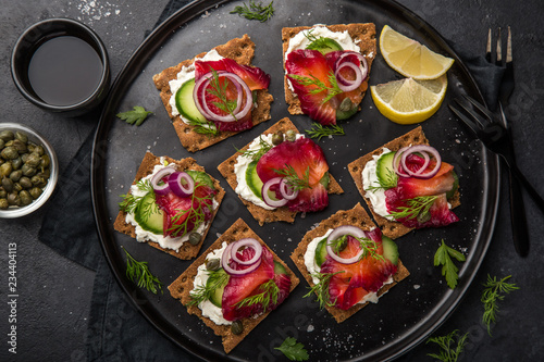 healthy sandwiches with wholegrain rye crisp bread, cream cheese, beet cured salmon and cucumber photo