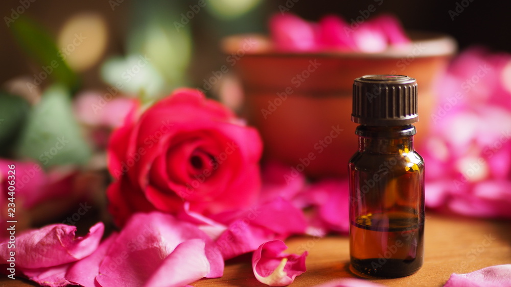 Clay bowl and aroma oil dark glass bottle among roses petals on the wooden table, natural raw material, selected focus, close up Clay bowl and aroma oil dark glass bottle among roses petals on the wooden table, natural raw material, selected focus, close up