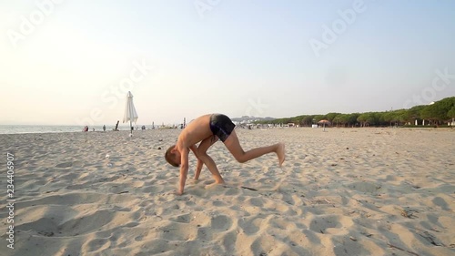 Little smiling child boy jumping on sea sand beach, slow motiion photo