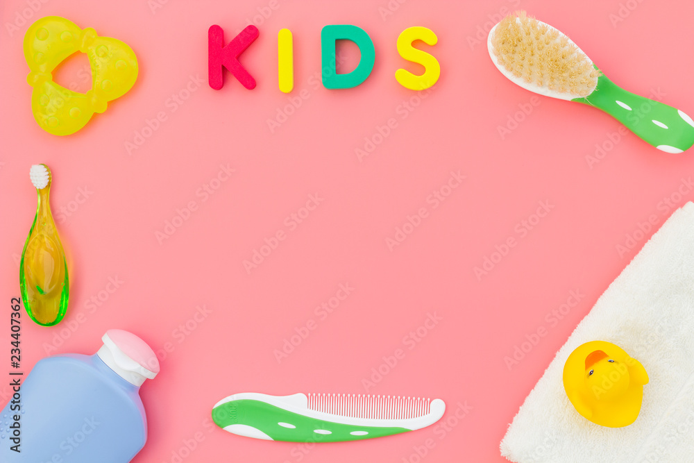 Hygiene items for the child. Bath accessories with yellow rubber duck on pink background top view copy space frame. Word KIDS