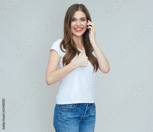 Smiling woman talking on cell phone doing thumb up.