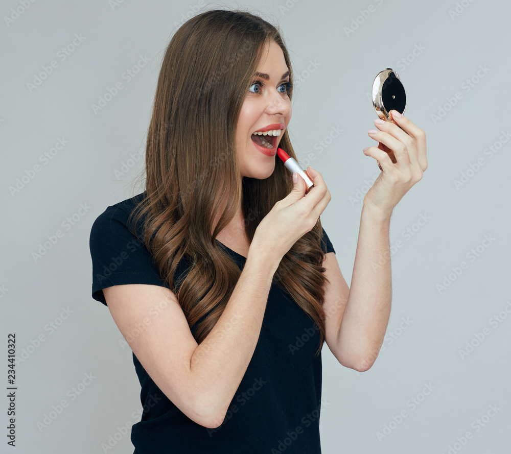 woman looking in cosmetic mirror painting lips woman looking in cosmetic mirror painting lips