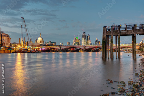 An old pier, the St Pauls cathedral, Blackfriars Bridge and the City of London at dusk