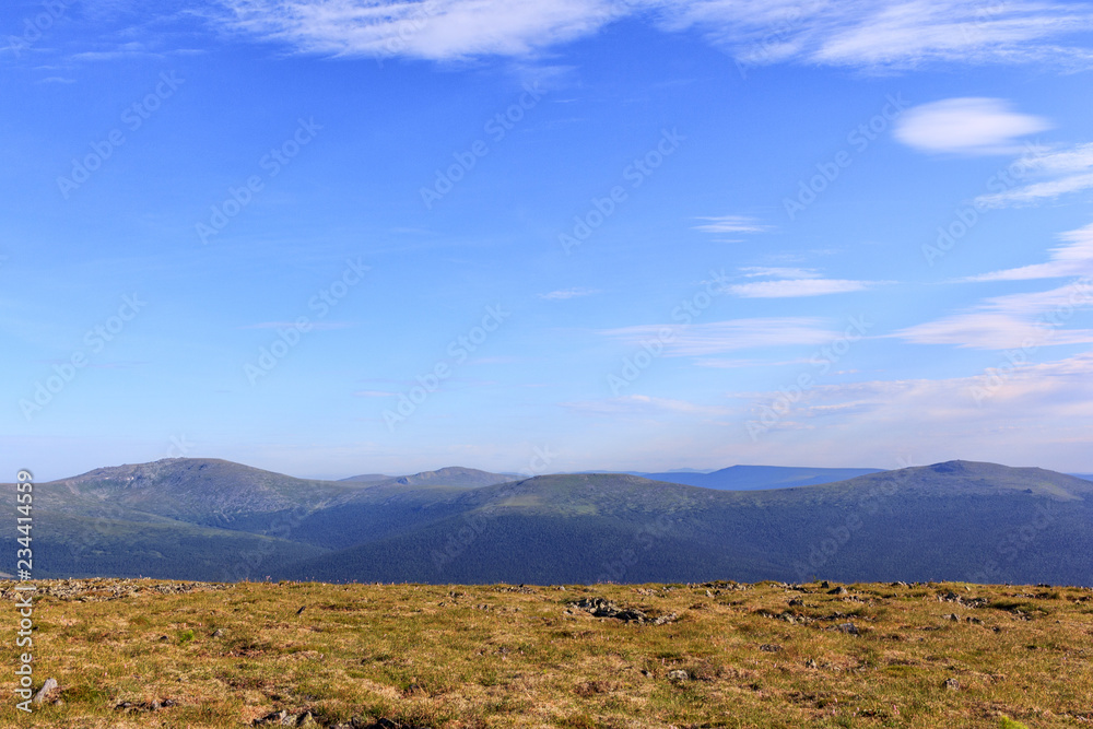 Beautiful card. Highlands valley and blue sky. Panoramic view of the mountain peaks.