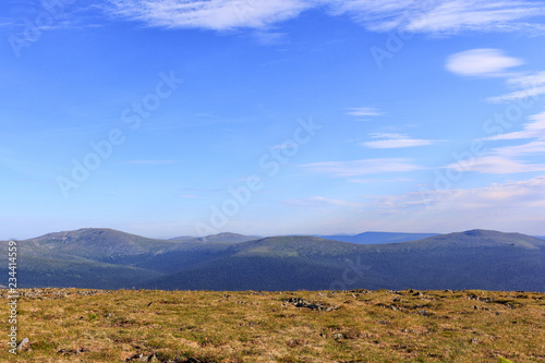 Beautiful card. Highlands valley and blue sky. Panoramic view of the mountain peaks.