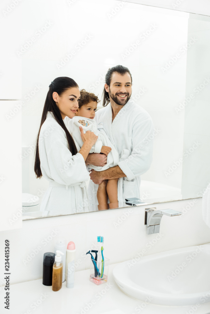 Family looking in mirror and smiling in white bathroom Family looking in mirror and smiling in white bathroom
