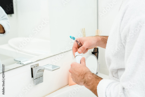 cropped view of male hands holding toothpaste and toothbrush in bathroom © LIGHTFIELD STUDIOS