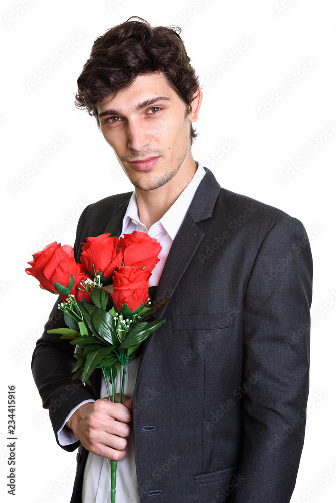 Studio shot of young handsome businessman holding red roses near Studio shot of young handsome businessman holding red roses near