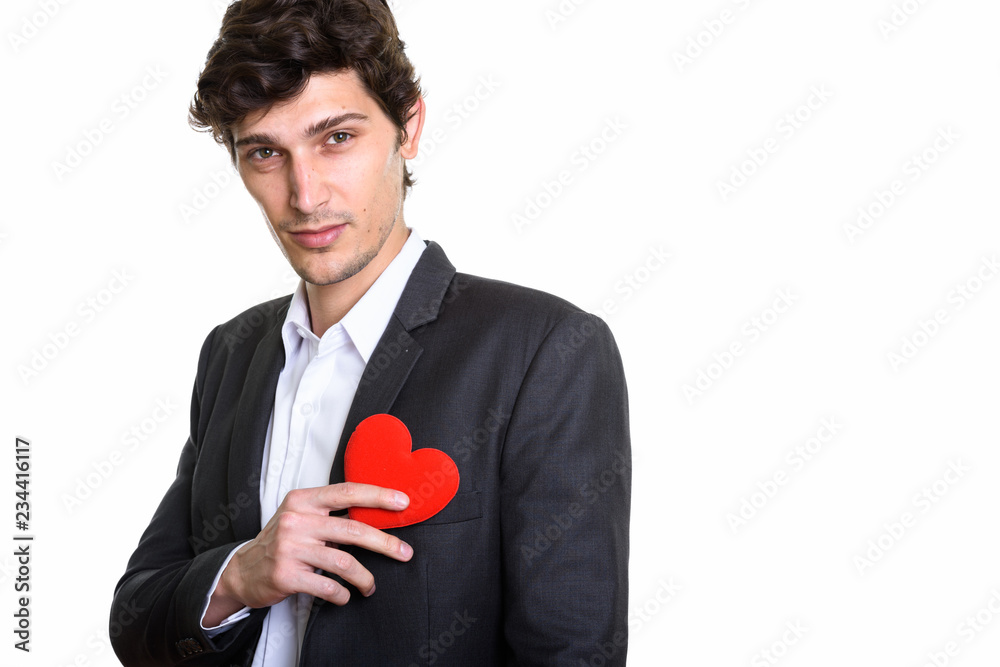 Studio shot of young handsome businessman holding red heart agai Studio shot of young handsome businessman holding red heart agai