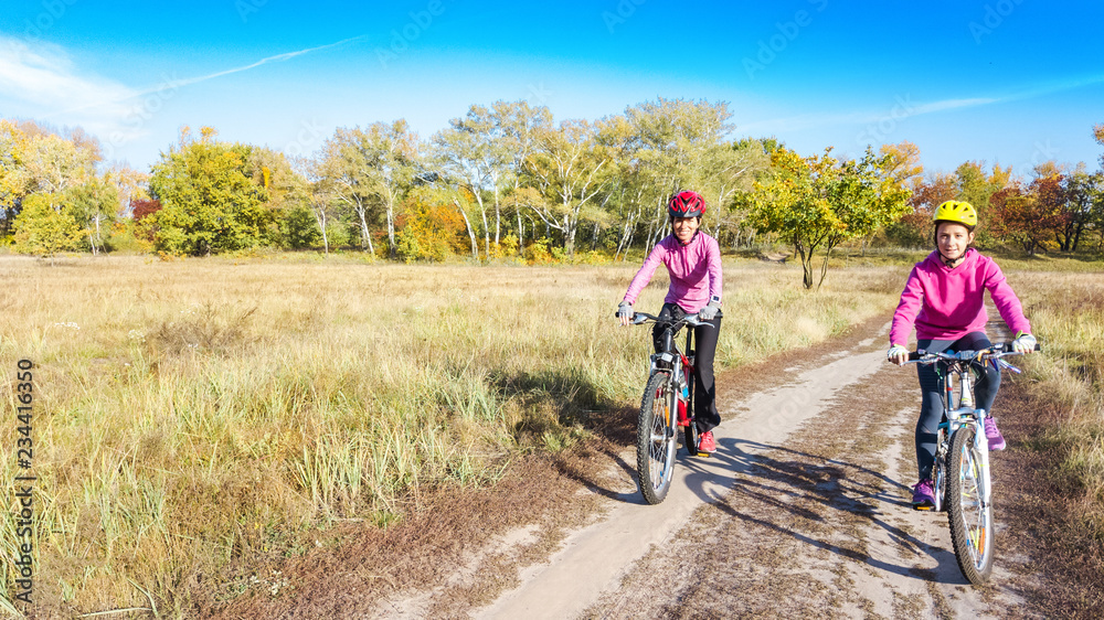 Fototapeta premium Family on bikes autumn cycling outdoors, active mother and kid on bicycles, aerial view of happy family with child in fall park from above, sport and fitness concept 