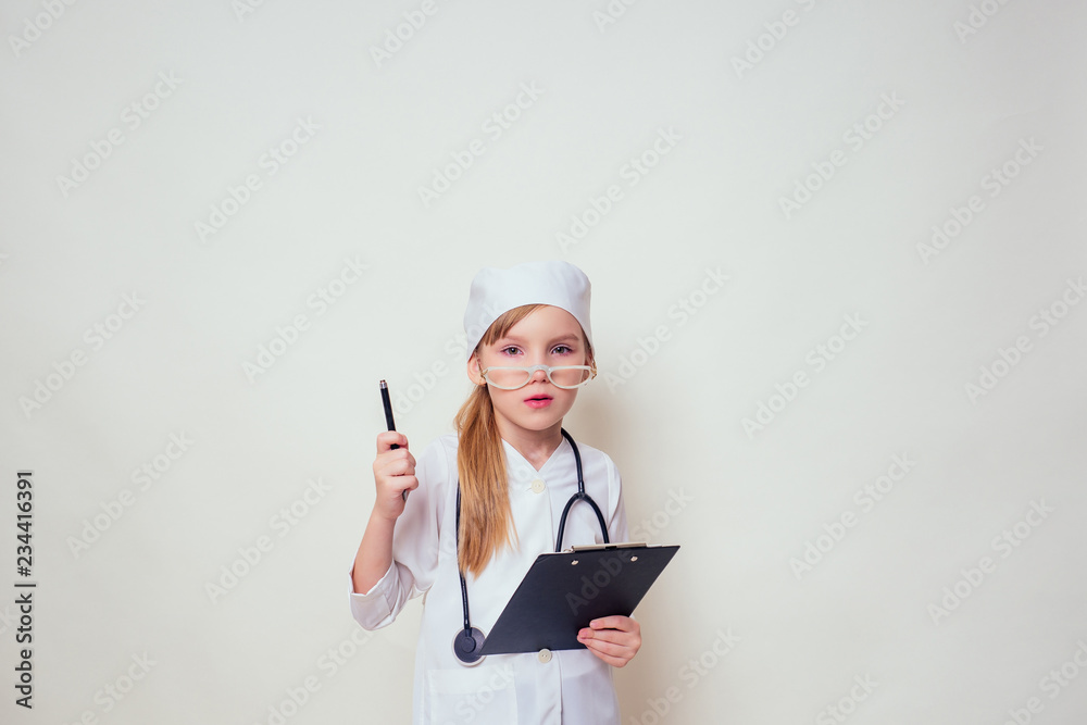 smiling little girl in doctor uniform with medical tools stethoscope writing something to clipboard on white background in studio copy space.future profession vocational guidance career smiling little girl in doctor uniform with medical tools stethoscope writing something to clipboard on white background in studio copy space.future profession vocational guidance career