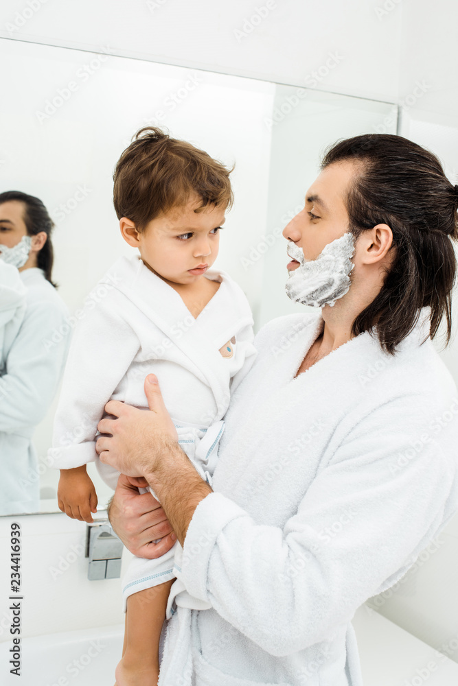 Obraz premium Dad holding toddler son at morning in bathroom