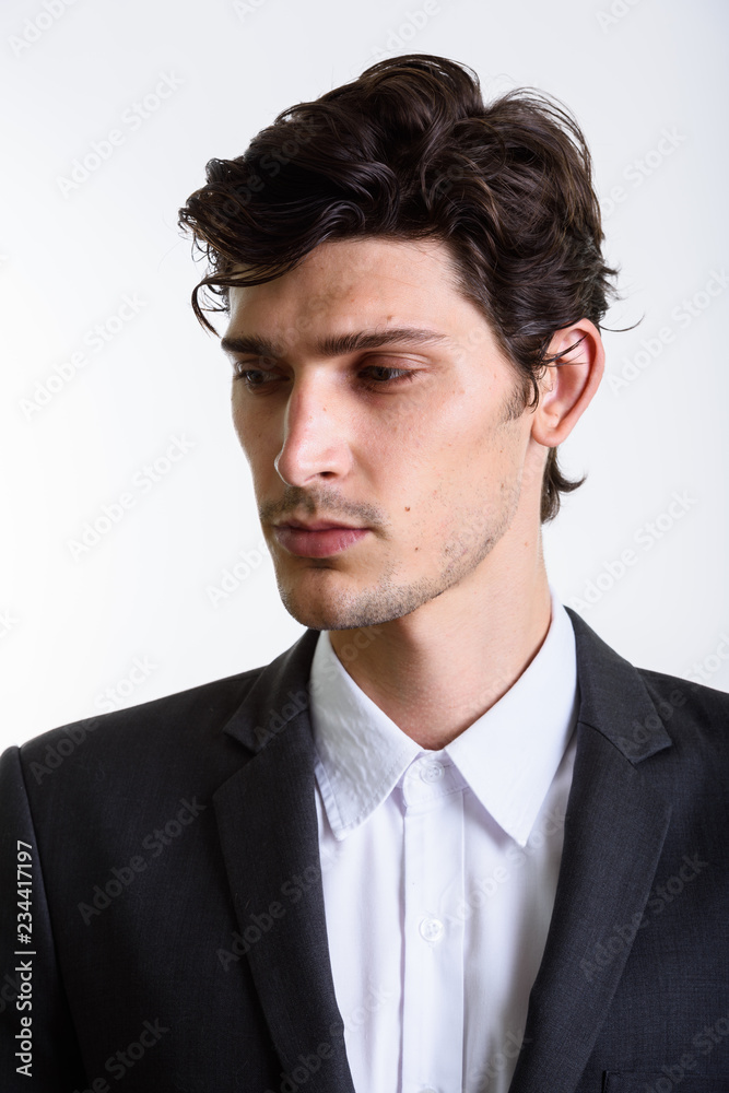Studio shot of young handsome businessman looking down