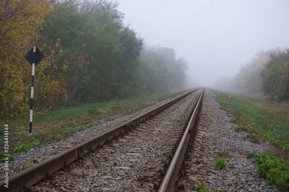Fototapeta premium Railway arrow in the thick fog in the autumn, the concept of decision making in conditions of uncertainty.