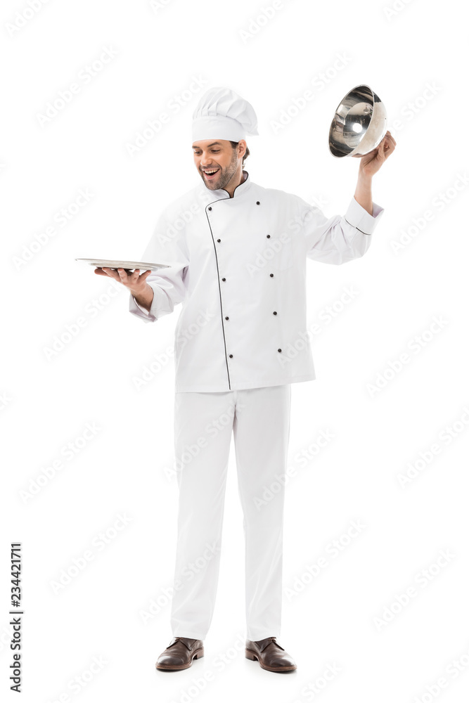 happy young chef taking of serving dome from plate isolated on white happy young chef taking of serving dome from plate isolated on white