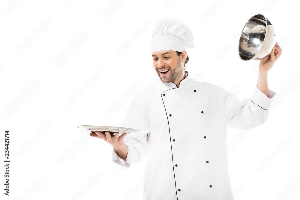 happy young chef taking of serving dome from plate isolated on white happy young chef taking of serving dome from plate isolated on white