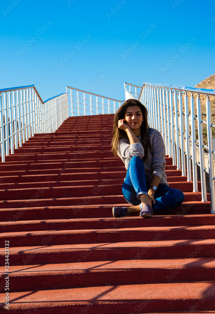 a young woman sitting and thinking on the red stairs a young woman sitting and thinking on the red stairs