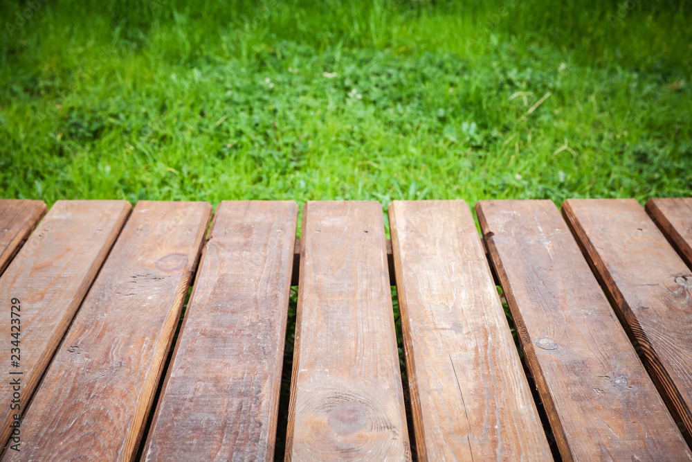 Fototapeta premium Wooden boards over lawn with green grass