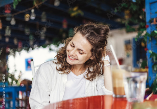 Portrait of beautiful cute cool happy smiling girl at a table in an outdoor cafe