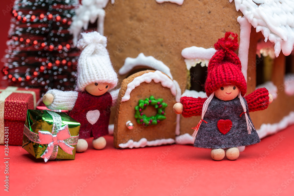 Cookie house with dolls and christmas tree on red background