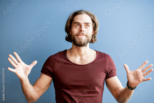 Portrait of a young caucasian bearded man with long hair dressed in t-shirt on the colorful background