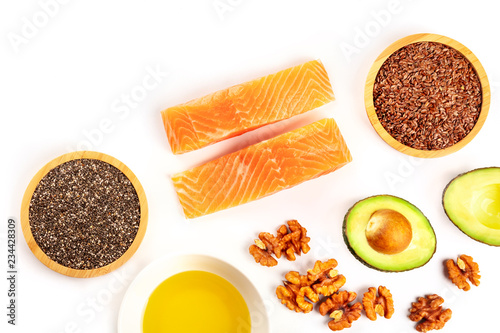 An overhead photo of healthy omega-3 diet food. Raw salmon, avocado, nuts, chia seeds, and flaxseeds, shot from above on a white background with copy space