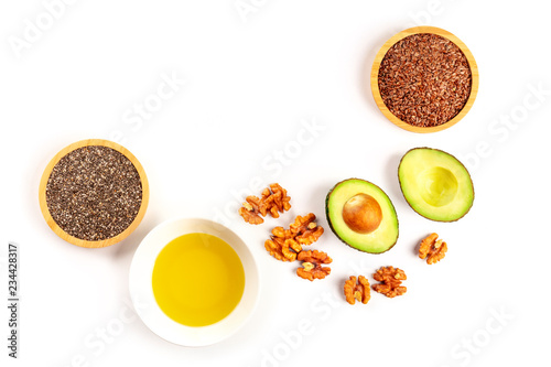 An overhead photo of healthy omega-3 vegan diet food. Avocado, nuts, chia seeds, and flaxseeds, shot from the top on a white background with copy space