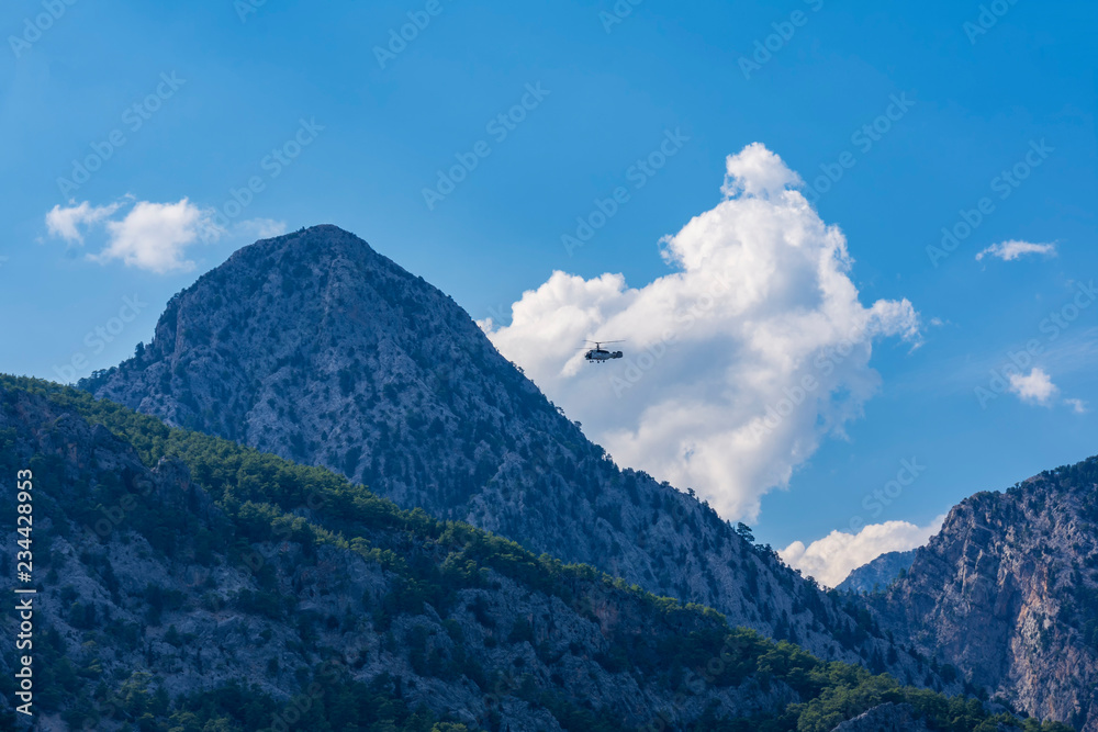 helicopter flight over the peak of the mountain, against the backdrop of mountains, blue sky and clouds