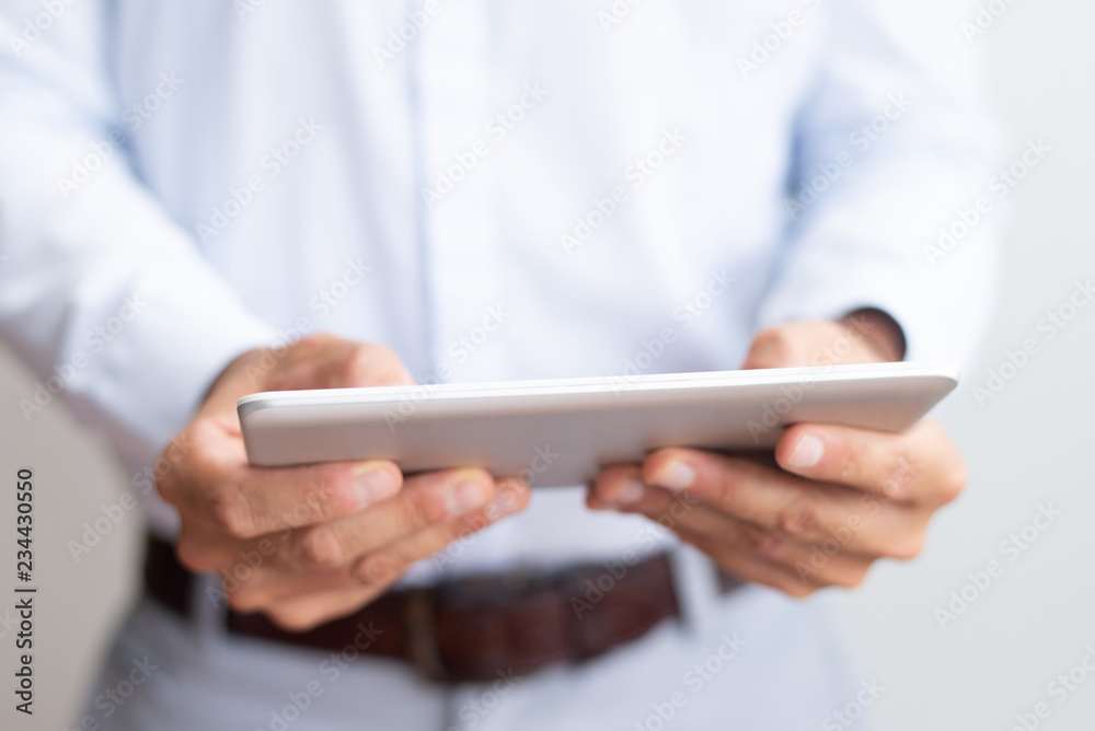 Closeup of business man using tablet computer. Man browsing on digital device. Technology and communication concept. Cropped front view. Closeup of business man using tablet computer. Man browsing on digital device. Technology and communication concept. Cropped front view.