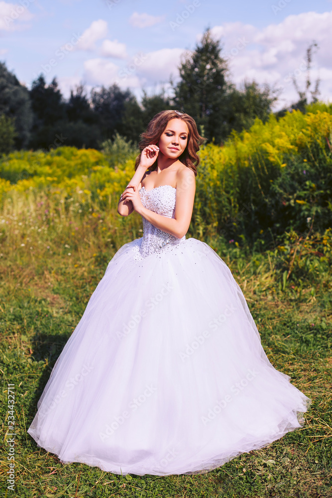 Bride in white dress walking in the park on a summer day