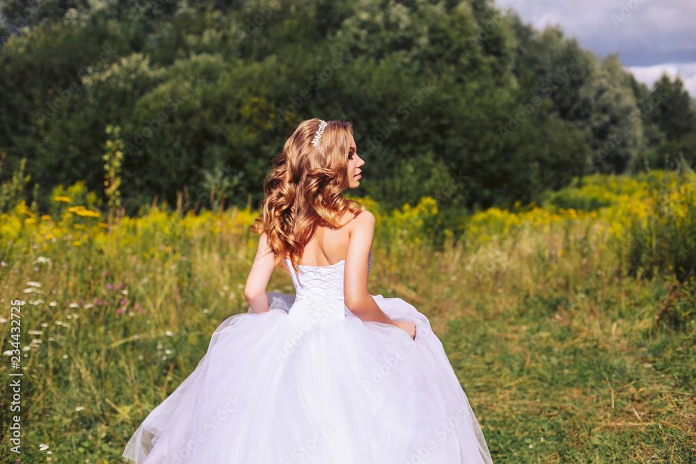 Young bride in a white dress in nature summer day