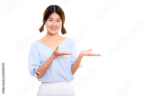 Studio shot of young happy Asian woman smiling while showing som