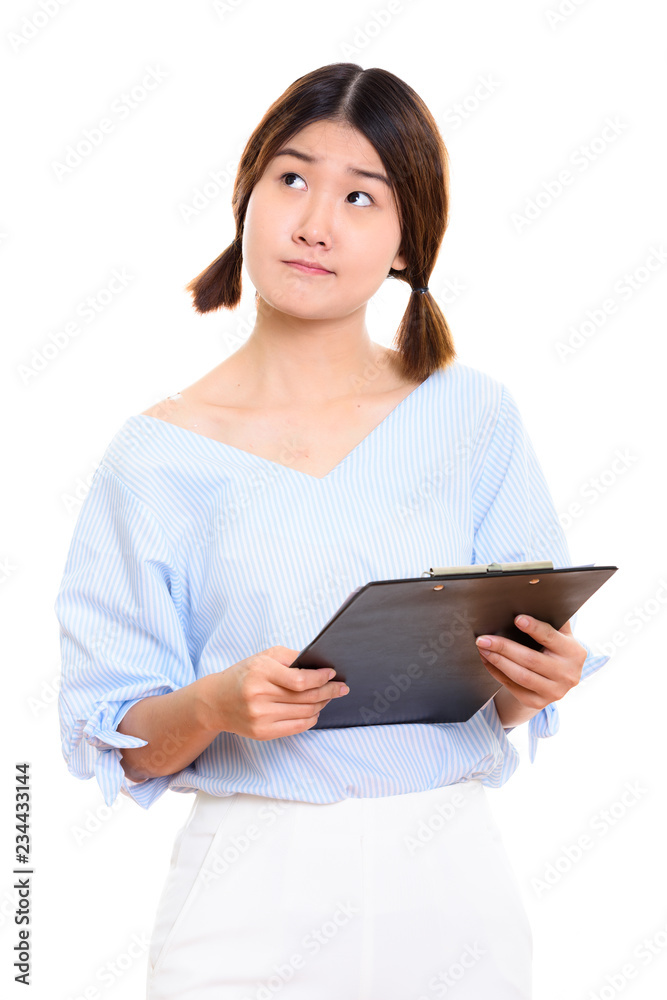 Studio shot of young beautiful Asian woman holding clipboard whi Studio shot of young beautiful Asian woman holding clipboard whi