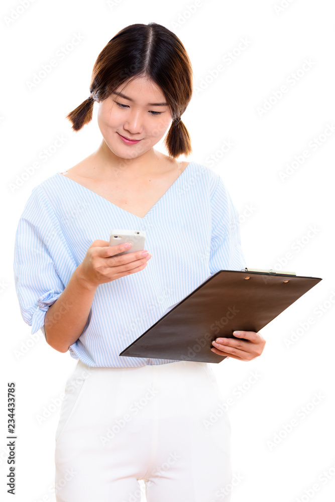 Studio shot of young beautiful Asian woman using mobile phone wh Studio shot of young beautiful Asian woman using mobile phone wh