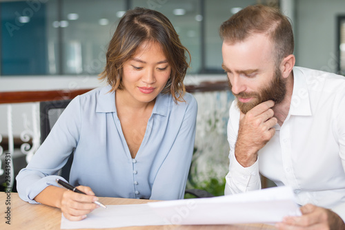 Pensive business experts analyzing marketing report. Two office workers studying and checking documents. Teamwork concept