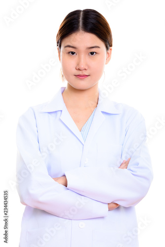 Studio shot of young beautiful Asian woman doctor with arms cros