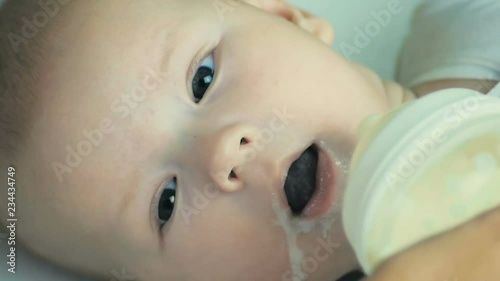 Close-up a mother feeds newborn boy with milk with feeding bottle in slow motion.