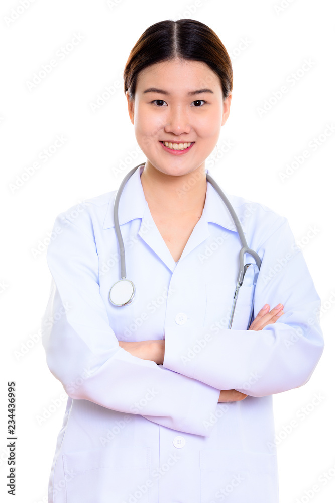 Studio shot of young happy Asian woman doctor smiling with arms Studio shot of young happy Asian woman doctor smiling with arms