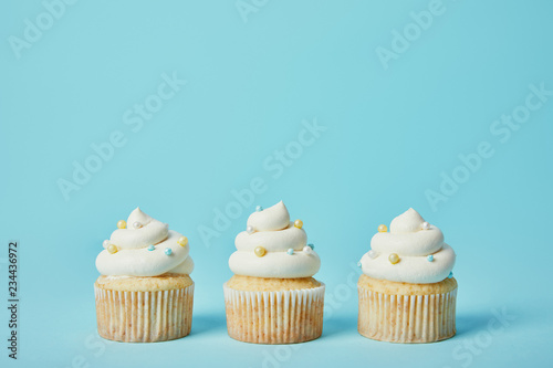 Tasty cupcakes with sugar sprinkles on blue background