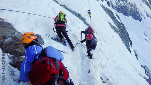 MONT BLANC, FRANCE - circa JUN, 2016: Mountaineers climb a snowy peak. In background the famous peak Dent du Geant in the Mont Blanc Massif, the highest european mountain. The Alps, Chamonix, France, Europ