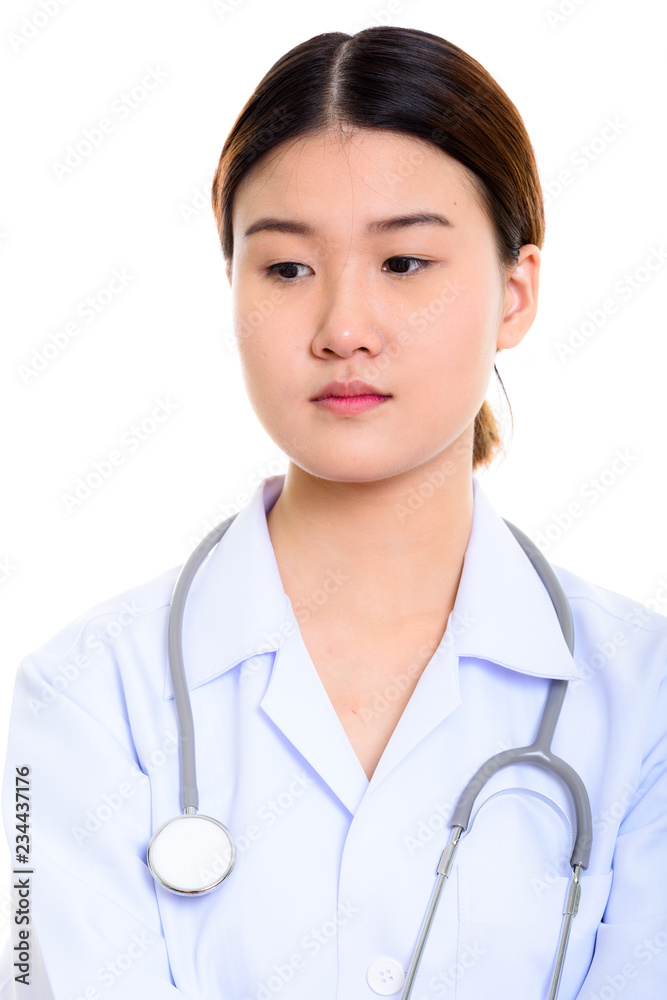 Studio shot of young beautiful Asian woman doctor thinking while Studio shot of young beautiful Asian woman doctor thinking while