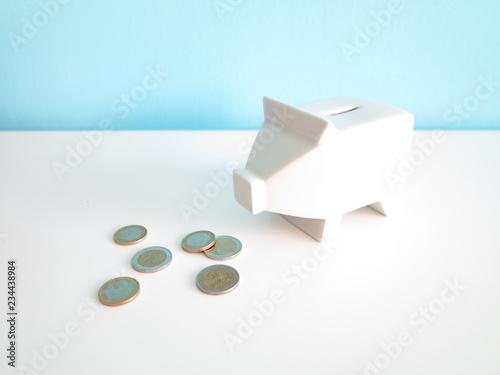 White ceramic piggy bank with euro coins on the table 