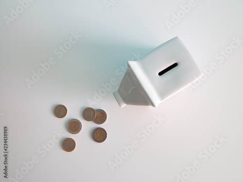 White ceramic piggy bank with euro coins on the table 