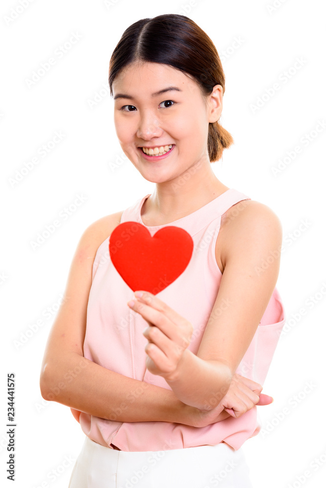 Studio shot of young happy Asian woman smiling while holding red Studio shot of young happy Asian woman smiling while holding red