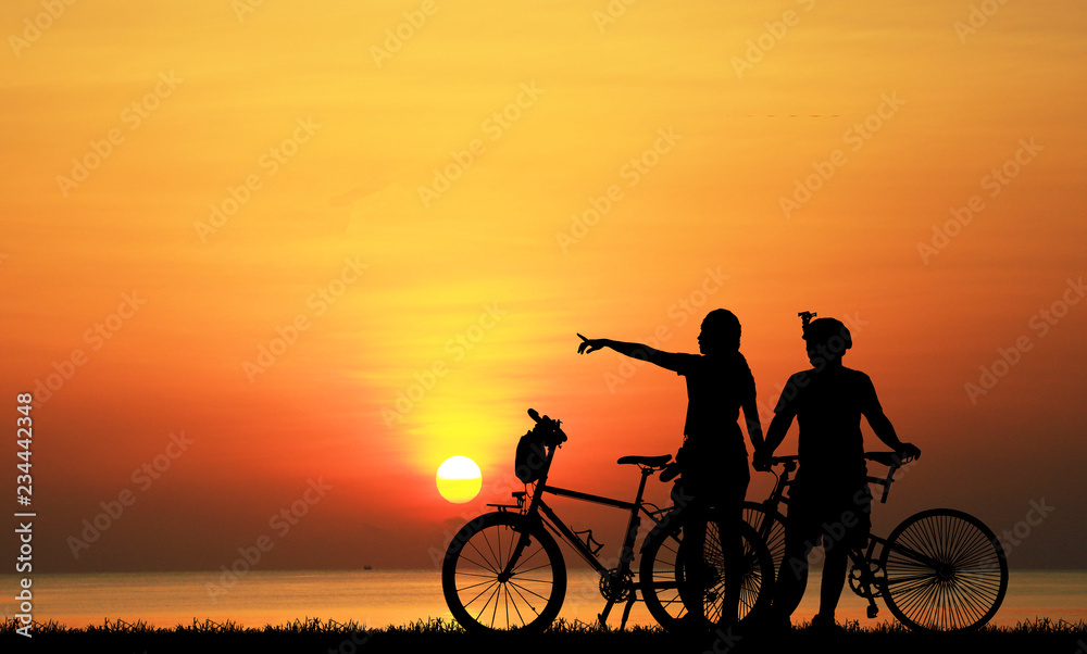Silhouette couple and bike relaxing on blurry sunset background. Silhouette couple and bike relaxing on blurry sunset background.